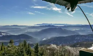Widok z wieży widokowej na Beskid Wyspowy. W dole las, w oddali pasmo górskie. To najładniejszy szlak na Mogielicę.