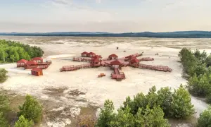 Pustynia Błędowska z widokiem na architekturę przypominającą różę wiatrów, z drewnianymi altanami i pomostami na piaszczystym terenie.