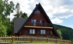 Drewniana bacówka PTTK na Maciejowej, schronisko turystyczne z Rabki, otoczone zielenią i drewnianym płotem.