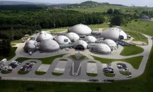 Kompleks kopuł przypominający bazę na planecie Alvernia, otoczony zielenią i lasem.