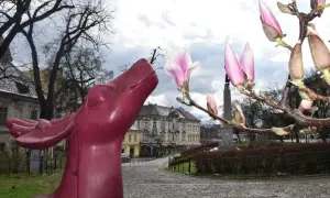 Różowa rzeźba jelenia na tle kwitnącej magnolii i kamiennych uliczek Cieszyna. Szlak magnolii w Cieszynie zaprasza do spacerów.