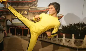 Bruce Lee w żółtym dresie wykonuje kopnięcie w powietrzu. Figura wosku w muzeum figur woskowych w Jastrzębiej Górze.