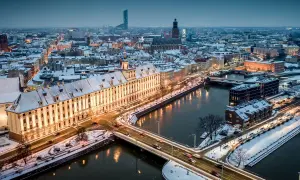 Zimowy Wrocław nocą. Ośnieżone dachy, rzeka i mosty tworzą magiczny widok. Warto odkrywać wrocławskie atrakcje zimą.