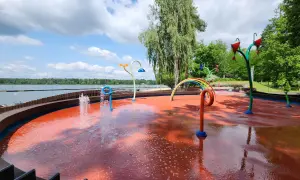 Kolorowy plac zabaw wodnych przy Jeziorze Paprocany, z fontannami i tęczą, zaprasza do zabawy w upalny dzień.