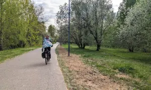 Osoba na rowerze jedzie ścieżką wzdłuż zielonego parku. To piękna pogoria 3 trasa, idealna na wiosenną przejażdżkę.