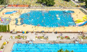 Tłum ludzi cieszy się słońcem i wodą w moczydło water park. W basenach i na trawie panuje wakacyjna atmosfera.