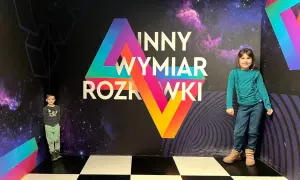 Dzieci w "Innym Wymiarze Rozrywki" w Warszawie. Kolorowa ściana z napisem i kosmicznym motywem tworzy niesamowite atrakcje dla dzieci.