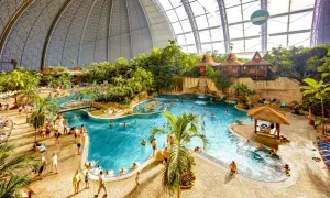 Wielki basen Tropical Island w Berlinie, z palmami, wodospadami i domkami na wodzie.