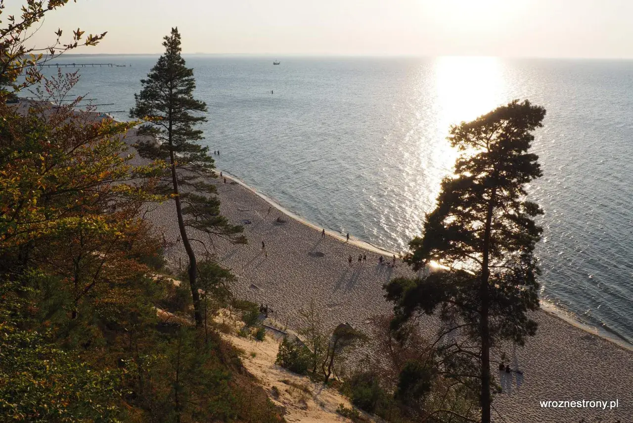 Zachód słońca nad Bałtykiem, złocący piaszczystą plażę i majestatyczne klify na wyspie Wolin.