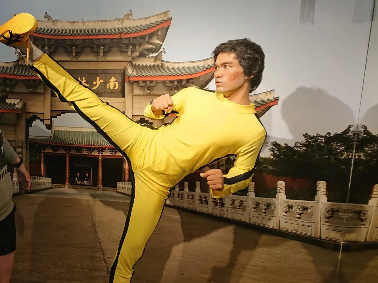 Bruce Lee w żółtym dresie wykonuje kopnięcie w powietrzu. Figura wosku w muzeum figur woskowych w Jastrzębiej Górze.