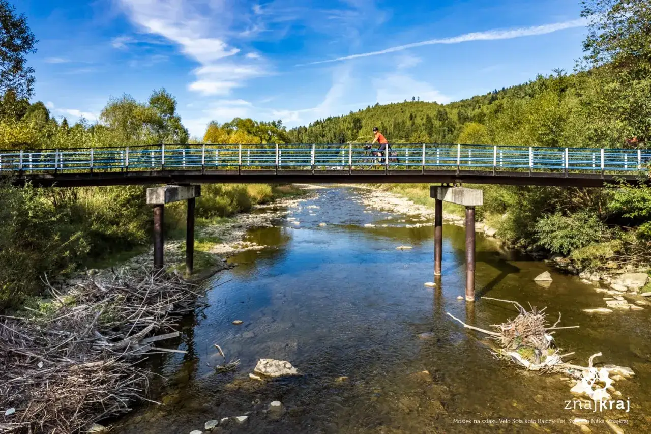 Rowerzysta na moście nad rzeką, odkrywający malownicze trasy rowerowe Żywiec.