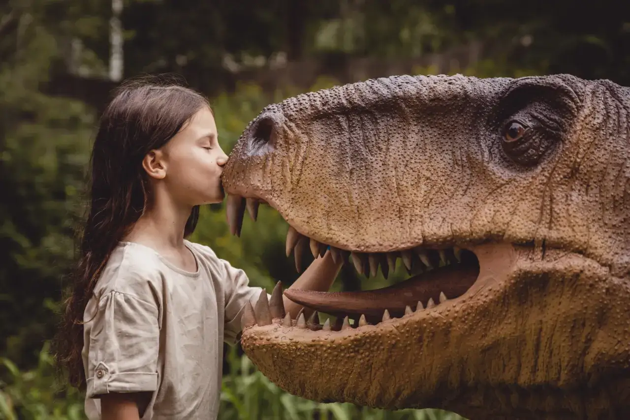 Dziewczynka całuje model dinozaura w jednym z parków dinozaurów w Polsce.