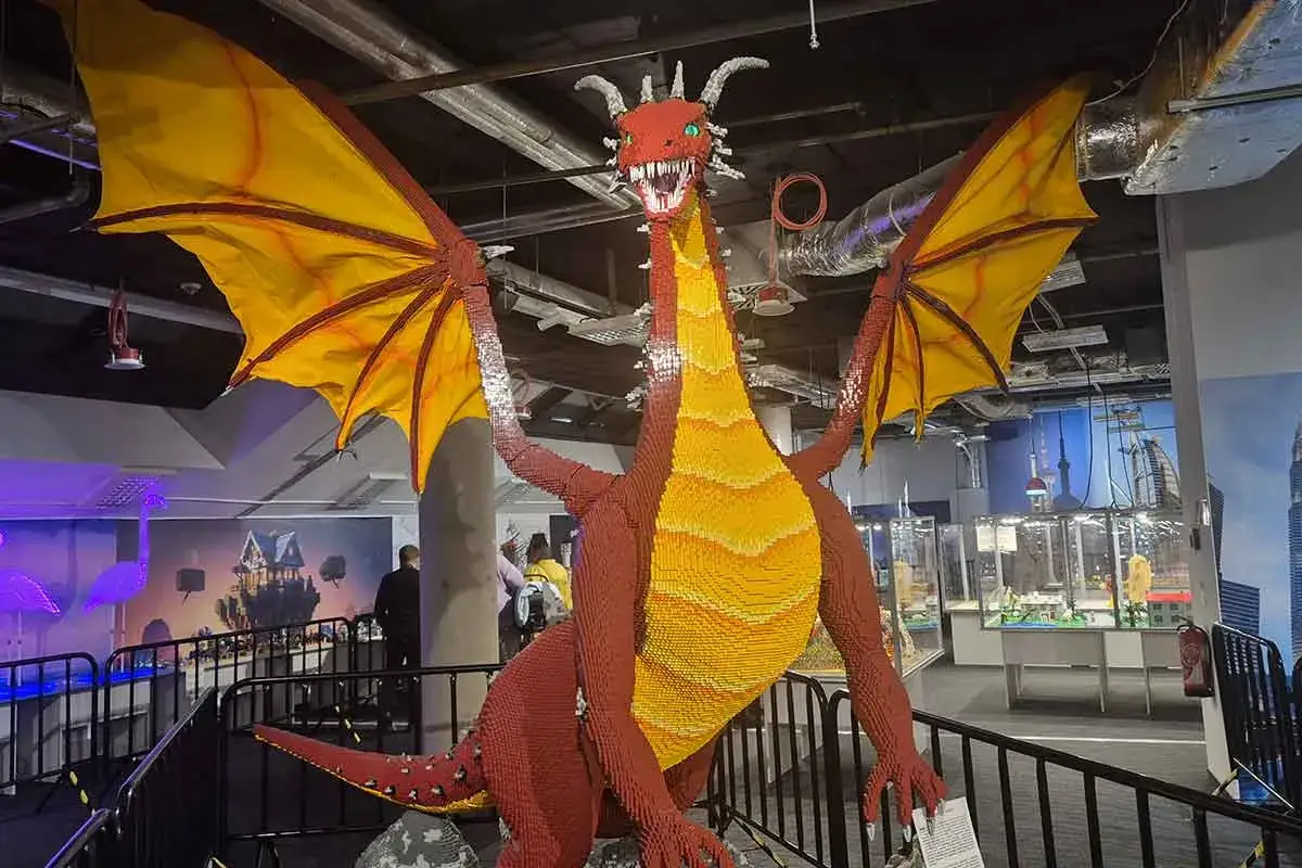 Smok z klocków LEGO wita w muzeum LEGO w Warszawie. Jego żółto-czerwone skrzydła i łuski budzą podziw.