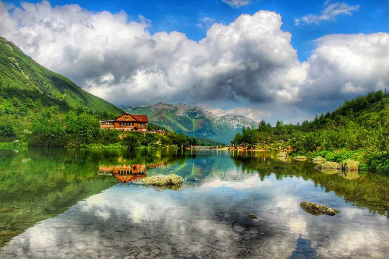 Zielone Pleso Schronisko nad krystalicznie czystym jeziorem, otoczone zielonymi wzgórzami i górami.